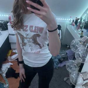 Säljer en vit t-shirt med trycket 'Wild Spirit' och två tigrar på framsidan. Texten 'Seoul 89' finns också med. Perfekt för en avslappnad stil.