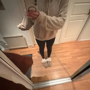 Beige hoodie i mjukt material - Mysig beige hoodie med dragsko i halsen. Tröjan har långa ärmar och en avslappnad passform, perfekt för kyliga dagar. Den är tillverkad i ett mjukt och bekvämt material som känns skönt mot huden.