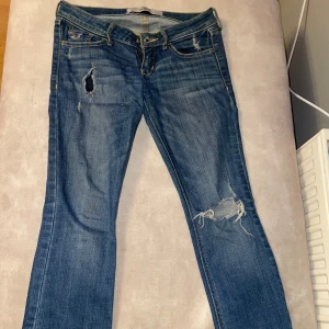 Blå jeans från Hollister - Snygga blå jeans från Hollister med slitna detaljer och låg midjande köpte för inte så länge sen. Midjemåttet är 37