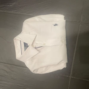 Vit skjorta från Polo Ralph Lauren - Snygg vit skjorta från Polo Ralph Lauren i slim fit. Skjortan har långa ärmar och en klassisk krage. Den är dekorerad med det ikoniska broderade logotypen på bröstet. Perfekt för en stilren look.