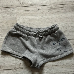 Grå Ma cherie shorts från Gina Young💓 - Säljer ett par grå shorts från Gina Tricot med elastisk midja och snörning. De har en söt stjärndetalj och texten 'Ma Cherie' tryckt på framsidan. Perfekta för en avslappnad stil.