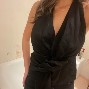 Svart omlott topp - Snygg svart omlott topp med knytning i midjan och djup urringning. 