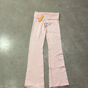 Ljus rosa yogapants från Gina Tricot strl 158/164 - Snygga och bekväma rosa yogabyxor från Gina Tricot. De har en ribbad hög midja och är perfekta för en avslappnad stil. Byxorna är gjorda i ett mjukt material som ger en skön känsla.Helt nya.