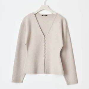 Beige kofta med knappar - Snygg beige kofta med v-ringning och knappar framtill. Perfekt för en stilren look, med långa ärmar och en mjuk finish. Slutsåld på hemsidan i xs, säljer inte under 500kr då skickar jag hellre tillbaka😊LAPPEN KVAR