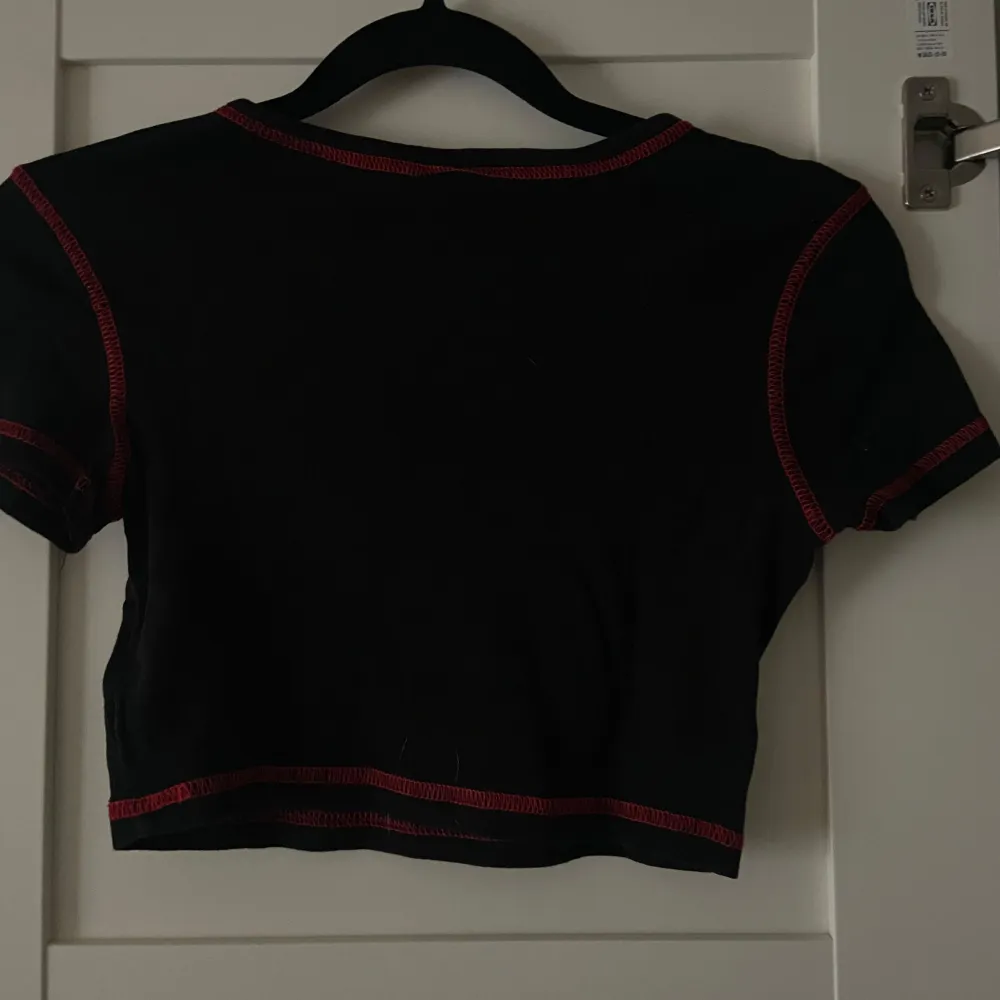 Säljer en svart croppad topp från H&M Divided med röd text och ormmotiv på framsidan. Används inte men är i toppen skick. . Yläosat.