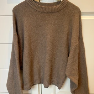 Brun stickad tröja från Nelly - Mysig brun stickad tröja från Nelly med ribbad rund hals och långa ärmar. Sitter väldigt fint avslappnat och oversized på. Som ny! 