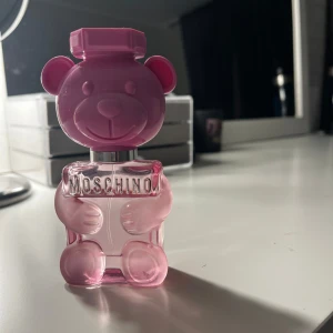 Parfym i nalleformad flaska från Moschino - Säljer en unik parfym från Moschino i en rosa nalleformad flaska. Parfymen doftar bubbelgum. Används lite men de mesta är kvar