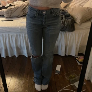 Lowwaist bootcut jeans - Blå jeans från Gina med hål på ena knät, ”full lenght flare”. Modellen är Midwaist men de sitter lowwaist, säljs inte längre. Jag har själv klippt av ca 3 cm längst ner (jag är 165 cm för referens)