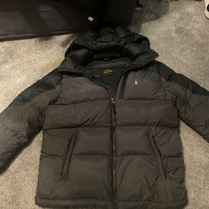 Säljer svart grå Ralph loaren vinter jacka - Säljer svart grå Ralph Loren jacka bra skick 8/10 inga skador på den har blivt för liten