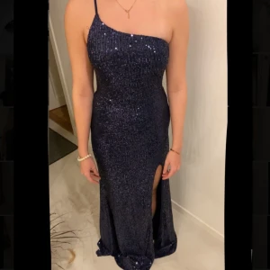 Marinblå balklänning i glitter med slitt  - Säljer min balklänning då jag köpt en annan! Endast prövat en gång och är helt oanvänd! Klänningen är i ett jätte fint tyg med massor av paljetter och med ett fint innertyg!  Är 165cm och har storlek xs   Ordinarie pris:1400