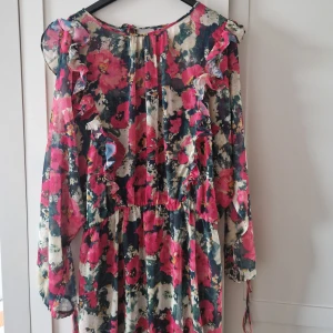 Chiffong klänning - En långärmad chiffongklänning från H&M, har använt den en gång och är i stl M.  Den har en grön underklänning och har knytband vid ärmsluten.  - Fraktar helst