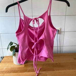Topp med öppen rygg  - Rosa topp med öppen / knytdetaljer i ryggen. Smala axelband och mjukt material. Från Weekday