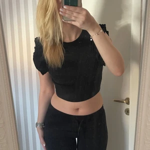 Svart ribbad topp från Zara - Säljer en superfin svart ribbad topp från Zara. Den har volangdetaljer på ärmarna som ger en extra touch. Perfekt för både vardag och fest! 🖤