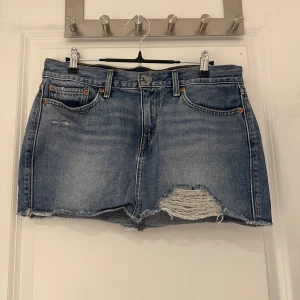 Kort jeanskjol Levis - Säljer denna supersnygga korta jeanskjolen från Levis med slitningar. Storlek W28, skulle säga att det motsvarar S/M. Precis som nyskick!