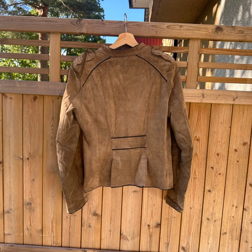 Snygg brun/grå mockajacka från Steinbock med knappar framtill och dekorativa axeldetaljer. Jackan har en klassisk design med två fickor och en figursydd passform. Perfekt för höst och vår! Från märket Jofama i storlek 36/S. Fint skick, men tecken på användning finns. Vanligt tecken som mockajacka får. . Takit.