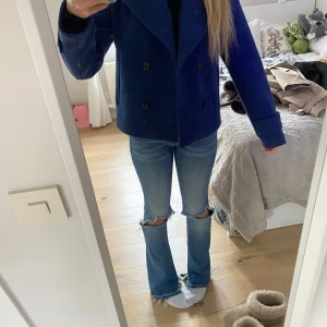  kappa från Kappahl - Säljer en snygg blå kappa från Kappahl i storlek XS. Den har en dubbelknäppt design med stora knappar och långa ärmar. 