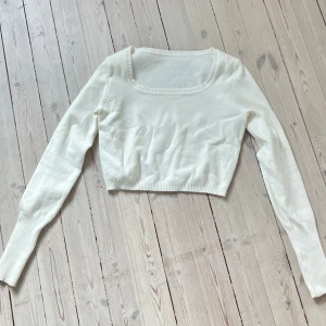 Vit croppad tröja - Säljer en stilren vit croppad tröja med långa ärmar. Perfekt för lager-på-lager eller som den är. Tröjan har en fyrkantig halsringning och är gjord i ett mjukt material. Passar till många olika outfits!