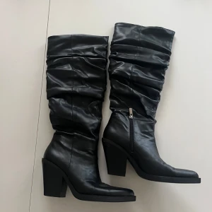 Svarta stövlar med klack - Snygga svarta stövlar i skinn med hög klack och dragkedja på sidan. De har en rynkad design, små i storleken. Väldigt bekväma!