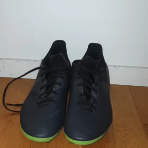 Jag har aldrig haft de på - Säljer ett par svarta fotbollsskor från Kipsta med gröna dobbar. Skorna har snörning och är perfekta för fotbollsträning eller match. De är designade för att ge bra grepp på planen.