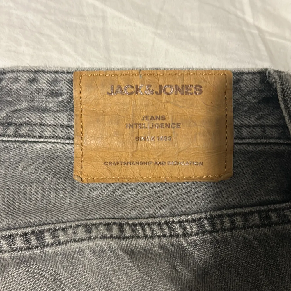 Säljer ett par grå jeans från Jack & Jones med en loose fit. De har en klassisk femficksdesign och en snygg tvättad look. Perfekta för en avslappnad stil.. Farkut & Housut.