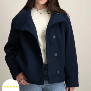 Mörkblå kappa med knappar - Snygg mörkblå kappa med stora knappar framtill. Jackan har en bred krage och är perfekt för kyligare dagar. Den har en stilren design som passar till många olika outfits. OBS! Inte precis den som är på bilderna. Vid intresse, fråga om fler bilder privat.
