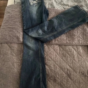 Blå jeans med broderade bakfickor - Snygga blå jeans med bootcut-stil och broderade detaljer på bakfickorna. Perfekta för en avslappnad look med en touch av stil. De har en klassisk femficksdesign och en bekväm passform.🩵