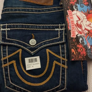 Blå jeans från True Religion - Snygga blå jeans från True Religion med kontrasterande sömmar och en unik broderad detalj på bakfickan.
