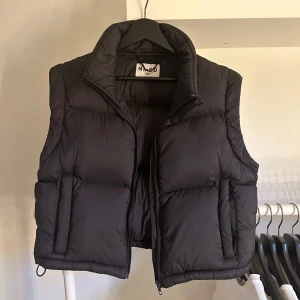 Svart dunväst - Svart kort dunväst med fickor framtill.