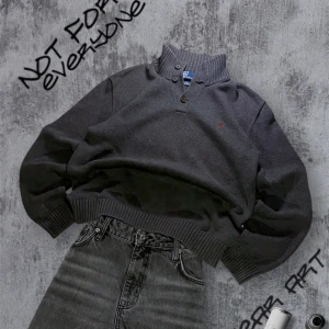 Stickad Ralph Lauren Tröja - Säljer en stickad grå tröja från Ralph Lauren i 100% bomull. Tröjan har en ribbad krage med tre knappar och ett diskret broderat logotyp på bröstet. Perfekt för en avslappnad och snygg look. Storlek M 