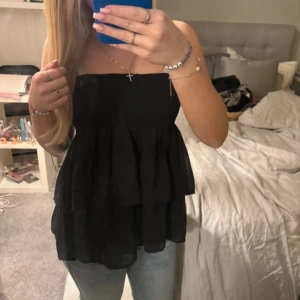 Svart kjol/topp - Snygg svart axelbandslös topp/kjol från KappAhl med volangdetaljer. Egentligen en kjol men passar lika bra som en topp!