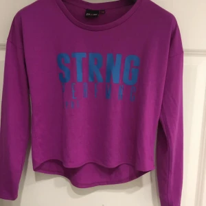 Lila tröja med tryck från Zara - Säljer en lila tröja från Zara med blått tryck 'STRNG PERFMC'. Tröjan är i en croppad modell med långa ärmar och är tillverkad i en blandning av polyester och viskos. Perfekt för en avslappnad stil. 💜