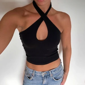 Svart halterneck topp korsad - Svart linne korsad i fram men går även att ha som vanlig halterneck