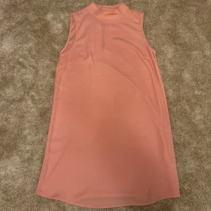 Rosa ärmlös klänning från H&M - Ärmlös klänning i en korallrosa nyans med en hög krage och en liten öppning baktill. Klänningen har en enkel och stilren design.  Kön: Kvinna Storlek: 44 Skick: 9/10 Ord: pris: 299 SEK    Din stil: spara inlägget så du inte missar denna kappa Inte din stil: Kolla min profil. Du kommer hitta något för alla kön och åldrar.