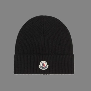 Svart mössa från Moncler - Snygg svart ribbad mössa från Moncler med broderad logotyp framtill. Perfekt för kyliga dagar och ger en stilren look. Passar både till vardags och mer uppklädda tillfällen. Vid mer frågor eller bilder, hör av er!🙌🏼
