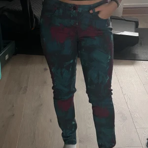 Färgglada jeans från Lee - Snygga jeans från Lee med ett unikt mönster i blått och lila. Byxorna har en klassisk femficksdesign och en dragkedja framtill. Perfekta för dig som vill sticka ut med en färgglad stil.