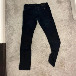 Mörkblå jeans från Nudie Jeans - Snygga mörkblå jeans från Nudie Jeans. De är i stretch denim material så de är både sköna och väldigt snygga. Färgen på bilder skiljer ifrån lite från verkligheten. 