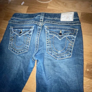  True Religion jeans  - Säljer ett par snygga blå jeans från True Religion med klassiska bakfickor och kontrastsömmar. De är nu lite uppsydda så det finns inte heller några skador längst ned. Säljer då de ej används.