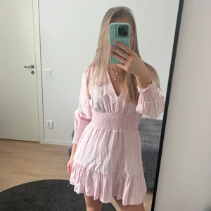 Rosa Zara klänning med volangdetaljer - Ljusrosa klänning med v-ringning och långa ärmar. Klänningen har en smockad midja och volangdetaljer vid fållen. Perfekt för sommaren och på midsommar!!💞💞 Säljer andra sommarkläder i min profil!
