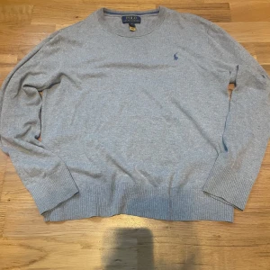 Grå tröja från Ralph Lauren - Säljer en grå tröja från Ralph Lauren med det klassiska loggan i blått på bröstet. Storlek 14-16 år/S. Hör av dig vid några frågor.