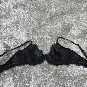Svart spets-BH - Elegant svart BH med spetsdetaljer och justerbara axelband. Perfekt för en stilren och sofistikerad look.