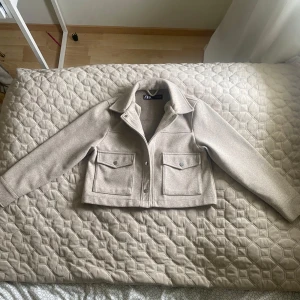 Beige kappa från Zara - Säljer en  beige kappa från Zara som är i nyskick. Användt 1-2 gånger. Säljer pågrund av att den inte kommer till användning. Kappan har långa ärmar och knappar framtill. Kappan har två stora fickor som är väldigt rymliga och längst upp har den en klassisk krage. Nypris 399 kr. Perfekt nu till våren men funkar även på hösten!! 🌸☀️Hör av er om ni har några frågor! 