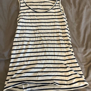 Randig linnetopp från Our Best Basics - Säljer en randig linnetopp från Our Best Basics i storlek S. Toppen är vit med svarta ränder och har en rund halsringning. Perfekt för en avslappnad stil.