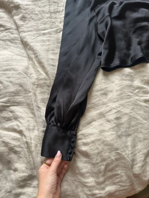 Blus - Svart blus från hm i storlek M med knappar på ärmen.