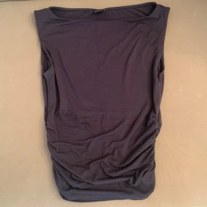 Topp - Mörkgrå linne/tshirt. Scrunch på sidorna av midjan. Sitter åt fint på kroppen. Får bysten se smickrande ut. Använd 2 gånger.
