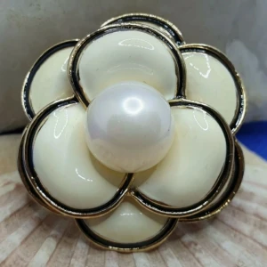 Brosch  - Vit Kamelia Blomma med stor pärla  - En brosch föreställande en Kamelia blomma, storlek ca 4x4cm.  Guldfärgad metall med vacker ytstruktur och emaljering samt en större pärla.  Grymt snygg brosch av hög kvalitet.