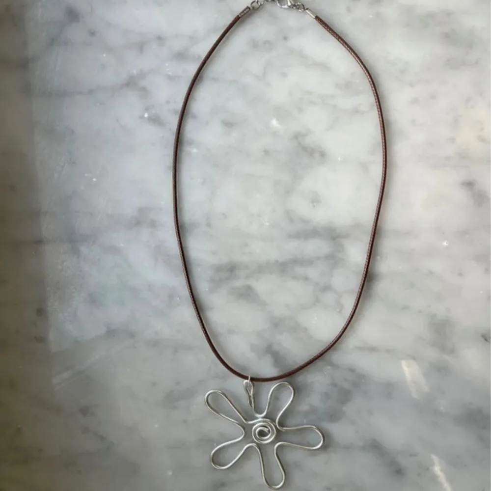 Egengjort halsband med berlock silvrig blomma gjort i aluminiumtråd, med brunt läderband/snöre, justerbart! . Accessoarer.