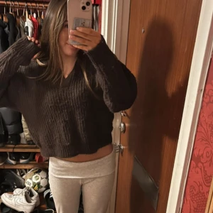 Brun stickad tröja - Säljer en mysig brun stickad tröja med v-ringning. Tröjan är croppad och har långa ärmar, perfekt för kyligare dagar. Passar bra till både jeans och leggings.