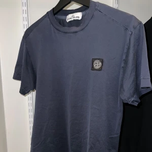 Mörkblå t-shirt från Stone Island i S - Snygg mörkblå t-shirt från Stone Island med korta ärmar och en broderad logotyp på bröstet. Perfekt för en stilren och avslappnad look. Storlek S.