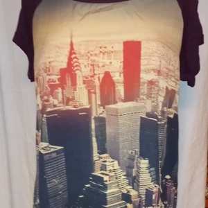 T-shirt med stadsmotiv från Amisu - Cool t-shirt från Amisu med ett häftigt stadsmotiv i rödbruna toner på framsidan. Baksidan är enfärgad i mörklila. Perfekt för en avslappnad stil.