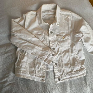 Vit jeansjacka från Mango - Säljer en stilren vit jeansjacka från Mango. Jackan har knappar framtill och två bröstfickor med knappdetaljer. Perfekt för vår och sommar! Står storlek L men den passar som en S 